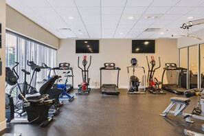 Et fitnesscenter med forskellig træningsudstyr, herunder løbebånd, motionscykler og elliptiske træningsmaskiner.