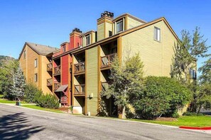 A multi-story building with balconies, a red staircase, and a green lawn. - Walk to Town/ Golf; Pool and Hot Tub (Park City)