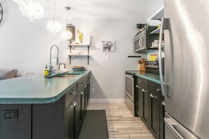 Una cocina moderna con una isla central, electrodomésticos de acero inoxidable e iluminación colgante.