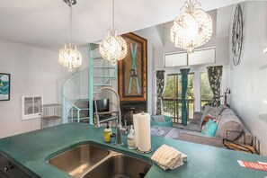A kitchen with a green countertop, a sink, and a spiral staircase. There is a living area with a sofa and a fireplace. - Walk to Town/ Golf; Pool and Hot Tub (Park City)