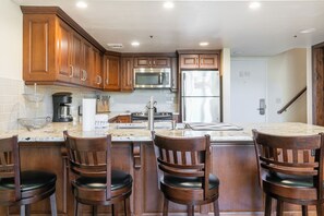 A kitchen with wooden cabinets, a stainless steel refrigerator, a microwave, and a sink. - True Ski In/ Out 3 BD Lodge at Mtn Village, Pool, Hot Tub, Fitness (Park City)