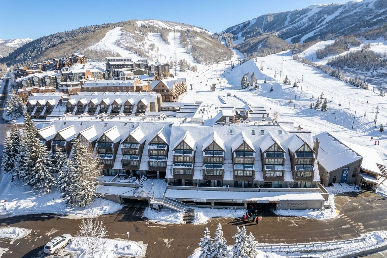Un grand hôtel doté de plusieurs ailes, avec une piste de ski en arrière-plan et un paysage enneigé.