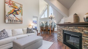 Ein Wohnzimmer mit Kamin, einer Couch, einem Hocker und einem Essbereich mit einer Chandelier.