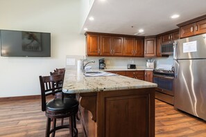 A kitchen with wooden cabinets, a stainless steel refrigerator, a microwave, and a coffee maker. - True Ski In/ Out 3 BD Lodge at Mtn Village, Pool, Hot Tub, Fitness (Park City)