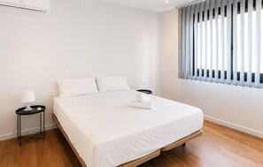 A minimalist hotel room with a wooden floor, a single bed, a nightstand, a lamp, and a window with blinds. - Stunning home in VINAROZ with private swimming pool, can be inside or outside (VINAROZ)