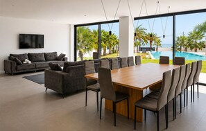 A modern living room with a large wooden table and chairs, a grey sofa, and a TV on the wall. - Stunning home in VINAROZ with private swimming pool, can be inside or outside (VINAROZ)