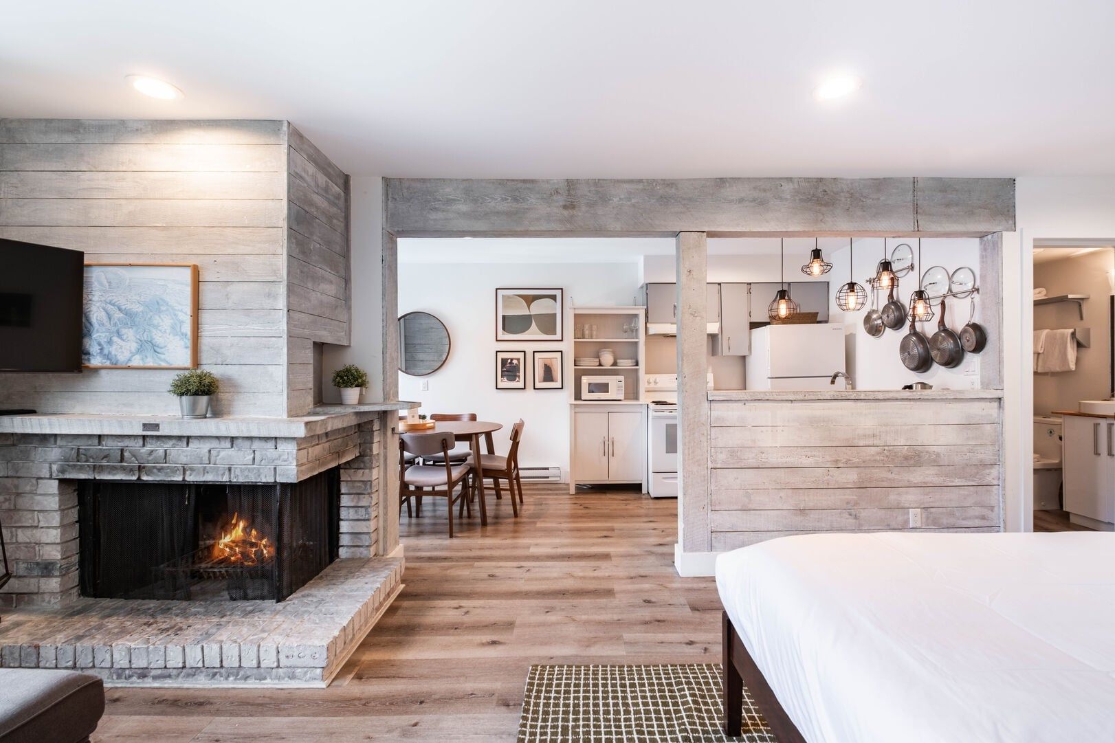 Decoração moderna com lareira, sala de jantar, cozinha e um quarto com cama grande.