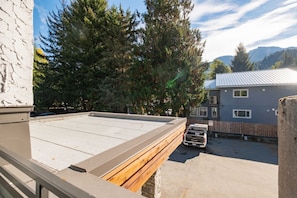 A rooftop terrace with a view of a forest and mountains. - Creekside | Walk to Gondola | Quiet Studio (Whistler)