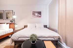 Une chambre d’hôtel avec un lit, des tables de chevet, une lampe, une plante et un tableau au mur.