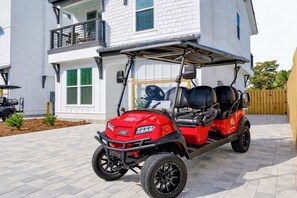 Un carrello da golf rosso parcheggiato davanti a un edificio bianco con un balcone.