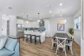 A modern kitchen with white cabinets, a stainless steel refrigerator, and a central island with bar stools. - Blue Pointe: Private heated pool, Free golf cart, 1min 2 beach, Game & Bunk room (Miramar Beach)