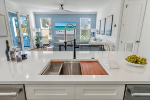A modern kitchen with a stainless steel sink, white cabinetry, and a view of the ocean through large windows. - Blue Pointe: Private heated pool, Free golf cart, 1min 2 beach, Game & Bunk room (Miramar Beach)