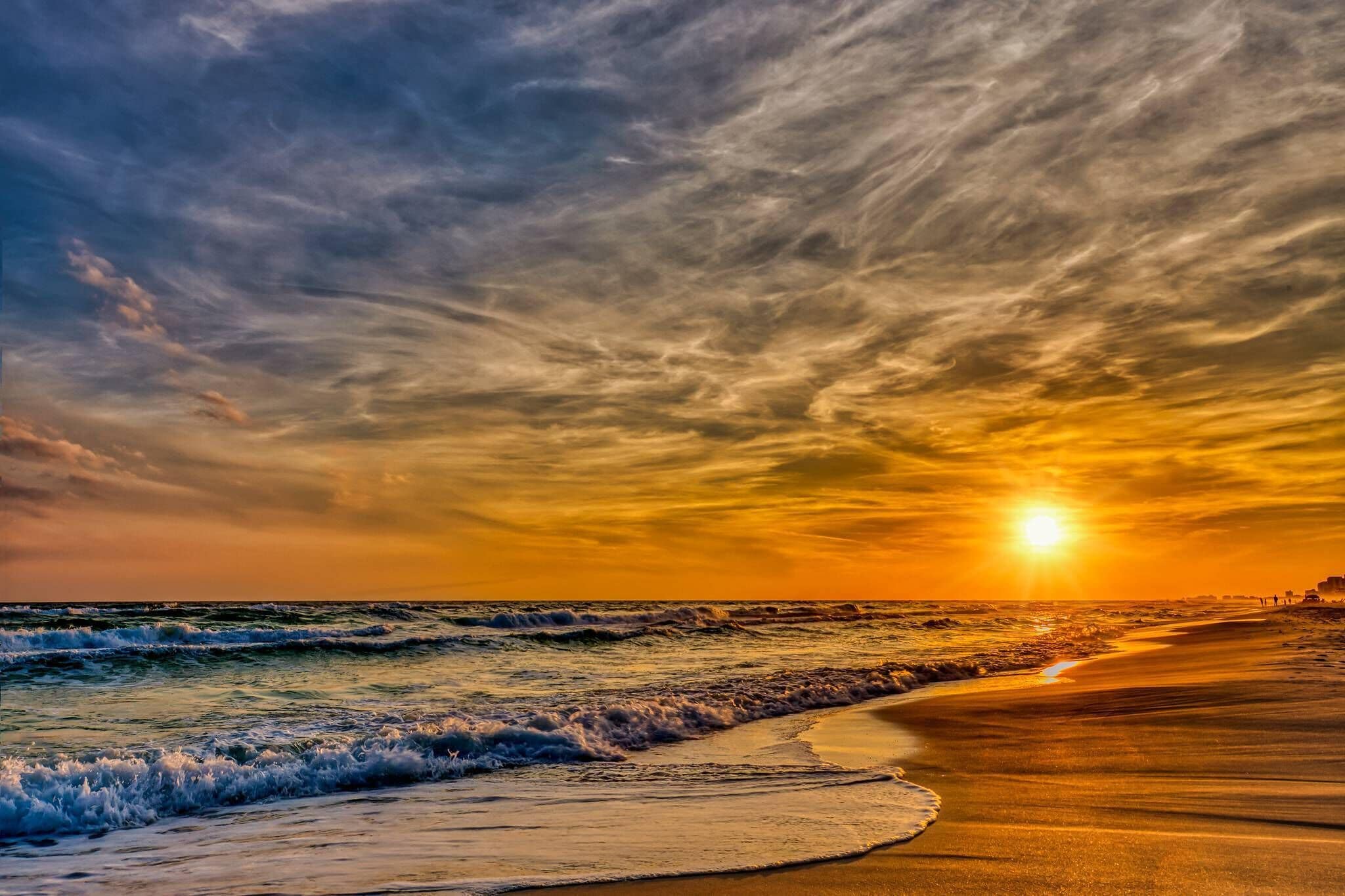 A beach with waves and a sunset.
