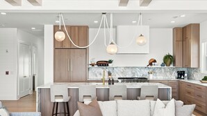Una cucina moderna con isola centrale, sgabelli da bar e mobili in legno.