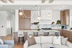 Eine moderne Küche mit einer zentralen Kochinsel, Barhocker und Holzschränken.