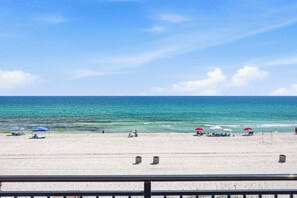 Una playa con sombrillas, sillas y una barandilla.