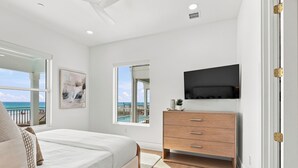 Una camera da letto con un letto, una cassettiera, una TV e una finestra vista oceano.