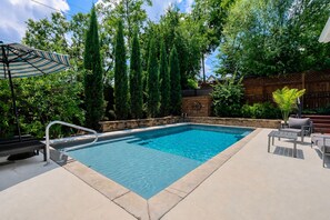 A rectangular swimming pool with a metal ladder, surrounded by a concrete deck. - 🌸 Magnolia House @ 12 South | Private Pool | Sleeps 10 | Fireplace (Nashville)