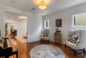 A spacious room with a piano, a round rug, two armchairs, a side table with a plant, and a framed picture on the wall. - 🌸 Magnolia House @ 12 South | Private Pool | Sleeps 10 | Fireplace (Nashville)