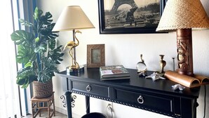 A desk with a lamp, a framed picture of the Eiffel Tower, a potted plant, and decorative items. - 2-bedroom condo-Fun Colorful-Fabulous Rancho Mirage- AC, pools, hot tubs, tennis (Rancho Mirage)