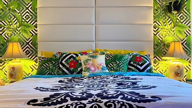 A bed with a patterned bedspread, multiple pillows, and two bedside lamps. - 2-bedroom condo-Fun Colorful-Fabulous Rancho Mirage- AC, pools, hot tubs, tennis (Rancho Mirage)