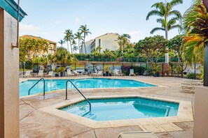 Ein Poolbereich mit zwei Pools, Liegestühlen, Palmen und einem Gebäude im Hintergrund.