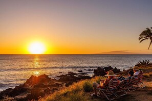 Ein Sonnenuntergang über dem Meer mit Menschen in Strandkörben.