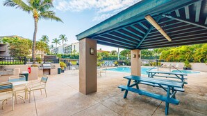 A covered outdoor area with a pool, picnic tables, and lounge chairs. - Modern Paradise | Kihei 2BR Near Beach (Kihei)