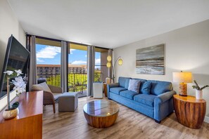 Ein stilvolles Wohnzimmer mit einem blauen Sofa, einem runden Couchtisch und einem Fernseher auf einem Lowboard.