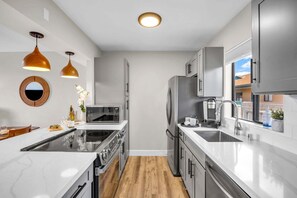 Een moderne keuken met een centraal eiland, roestvrijstalen apparatuur en hanglampen.