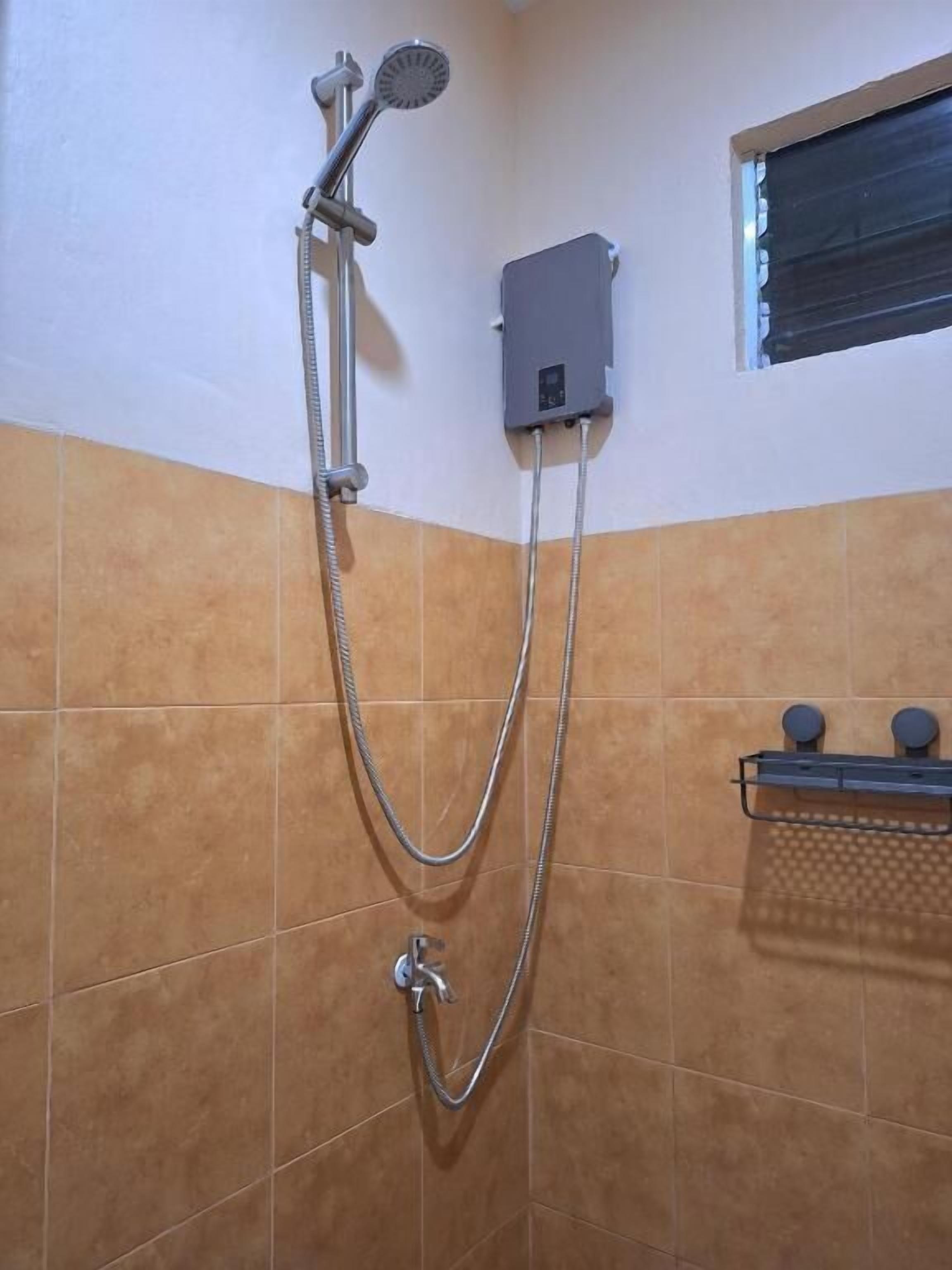 A shower with a handheld showerhead and a wall-mounted control box.