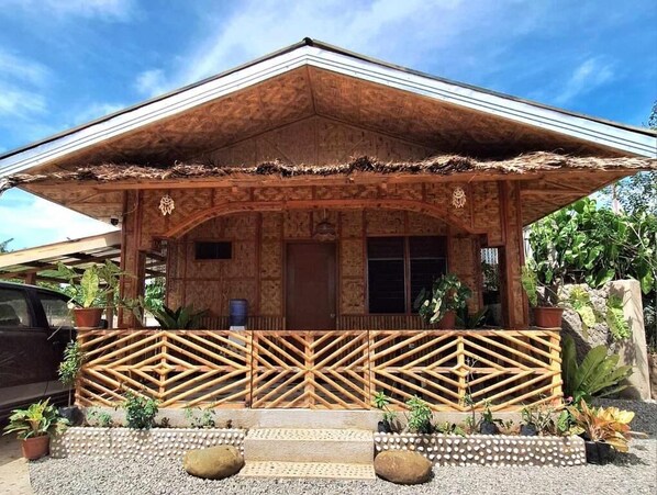 A wooden house with a thatched roof, a wooden fence, and potted plants. - Casas de Ruumar B&B (Clarin)