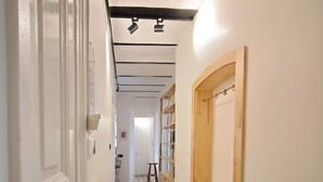 Ein schmaler Flur mit einem sternförmigen Boden, Holzschränken und einer weißen Tür.