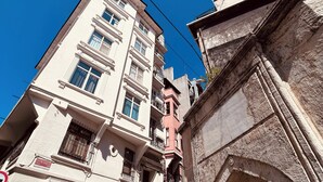Ein mehrstöckiges Gebäude im traditionellen Baustil, mit Balkonen und einem Eingang zur Straße.