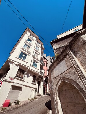 Ein mehrstöckiges Gebäude im traditionellen Baustil, mit Balkonen und einem Eingang zur Straße.