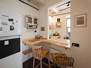A compact kitchen with a built-in stove, a wooden chair, a radiator, and a mirror reflecting the kitchen area. - 1910 Pera Apartment • 2BR Home • Istiklal & Galata (İstanbul)