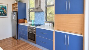 A modern kitchen with blue cabinets, a stainless steel refrigerator, and a built-in oven. - Randalsea - 15 Finniss Vale Drive (Second Valley)