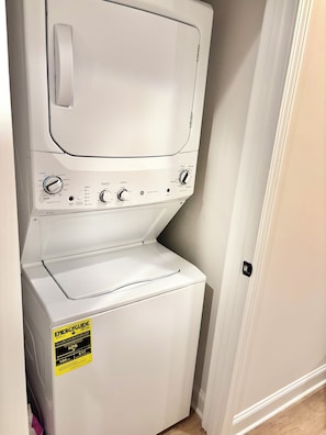 A white stacked washer and dryer unit with control knobs, a start button, and an ENERGY GUIDE sticker. - 3-bedroom Townhome in Serene Uptown Charlotte (Charlotte)