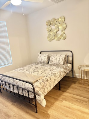 A bedroom with a metal bed frame, patterned bedding, a wall-mounted circular decoration, and a small round table. - 3-bedroom Townhome in Serene Uptown Charlotte (Charlotte)