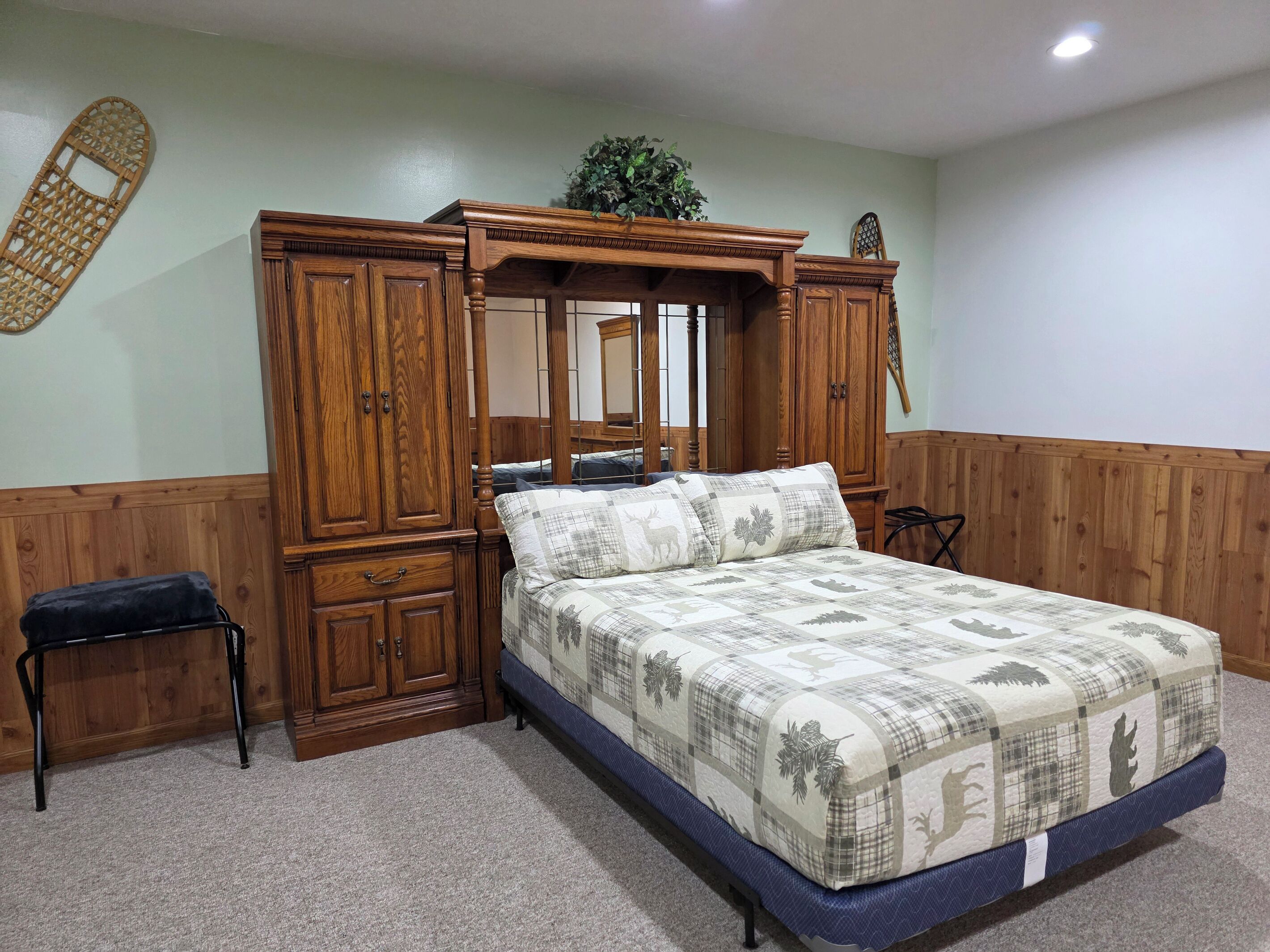Une chambre à coucher avec un lit à baldaquin, une armoire en bois, un petit tabouret et un miroir.