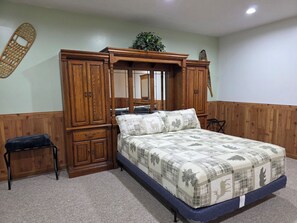 Ein Schlafzimmer mit Himmelbett, Holzschrank, kleinem Hocker und Spiegel.