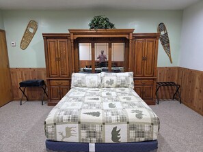 Un dormitorio con una cama grande, un armario de madera y dos sillas.