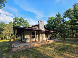 A cabin with a covered porch, a chimney, and a brick foundation. - Club 39 Lodge Private 5 Acres + Hot Tub (Luther)