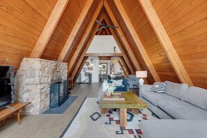 An attic room with a stone fireplace, a sofa, a coffee table, and a ceiling fan. - River Frontage•Pet Friendly•Renovated Luxury (Howard)