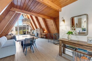 An attic room with a dining table, chairs, a sofa, and a large mirror. - River Frontage•Pet Friendly•Renovated Luxury (Howard)