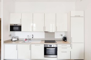 A modern kitchen with white cabinets, a built-in oven, a microwave, and a kettle. - Upstays Spacious 77m² T3 Apartment with Terrace (Cannes)
