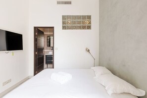 Une chambre à coucher avec un lit, un téléviseur fixé au mur, un placard et une fenêtre donnant sur un beau paysage.