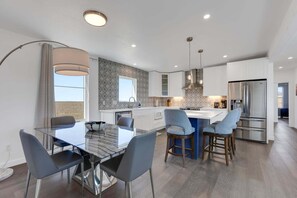 A modern kitchen with a central island, stainless steel appliances, and a dining area with a glass table and chairs.