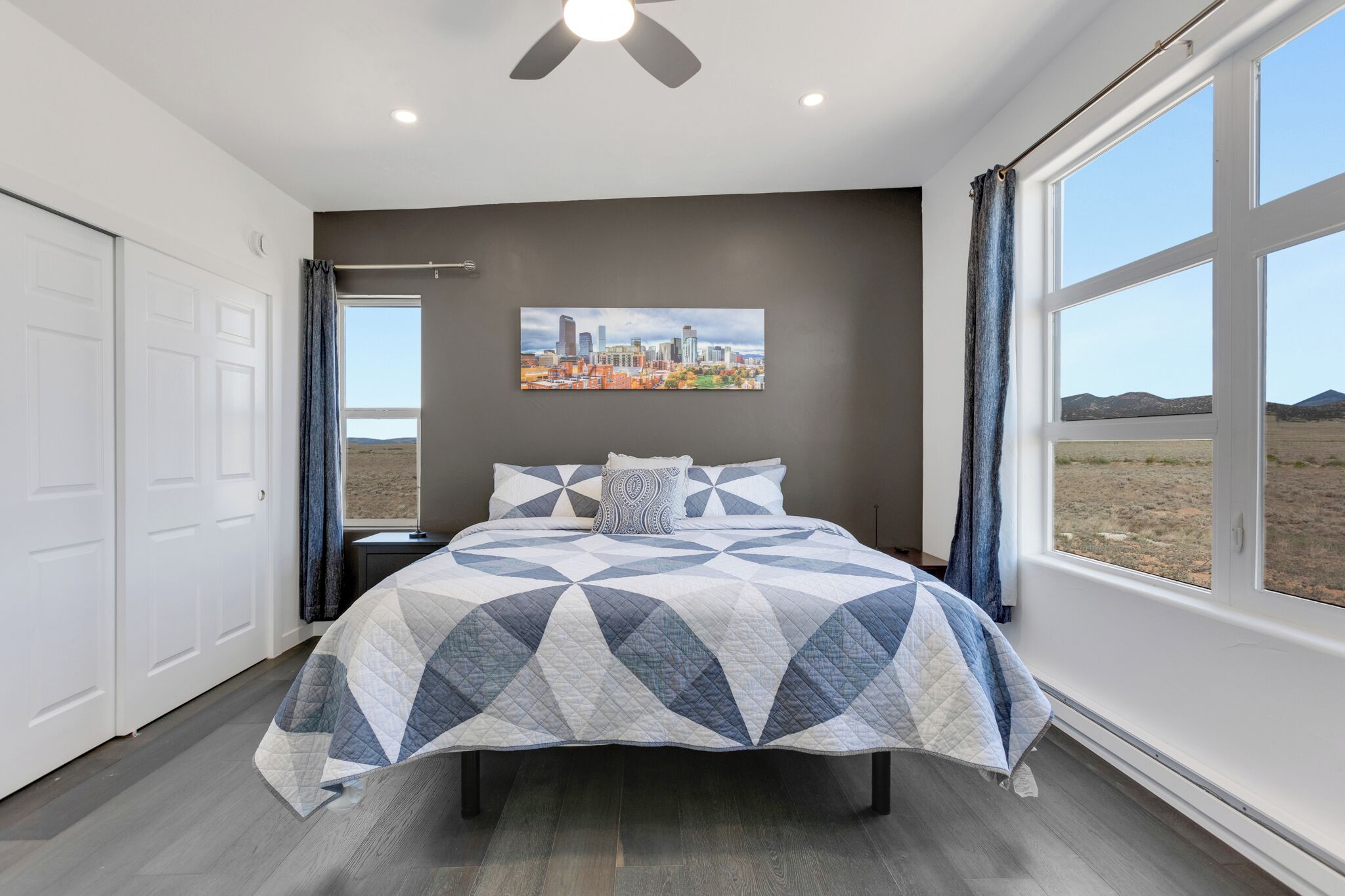 Een slaapkamer met een bed, een stadsgezichtschilderij en uitzicht op de woestijn.