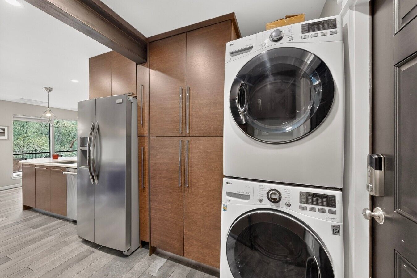 Une cuisine moderne dotée d’appareils électroménagers en acier inoxydable, de meubles en bois et d’un lave-linge et d’un sèche-linge intégrés.